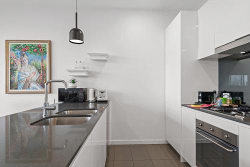 a white kitchen with a sink and a counter at A taste of paradise in inner city suburbia in Melbourne