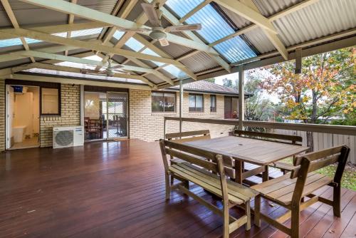 an open patio with a wooden table and benches at Spacious and Restful Holiday Home with Backyard in Weetangerra
