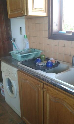 a kitchen with a sink and a washing machine at Miltos Apartment in Argaka