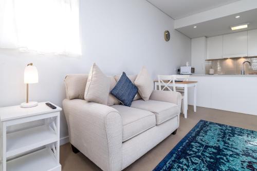 un salon avec un canapé blanc et une cuisine dans l'établissement Exquisite Apartment with BBQ and Pool, near Shops, à Phillip