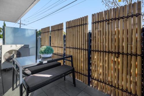 a fence with a table and a bench on a patio at Cosy 1-Bed with Private Balcony By Showgrounds in Melbourne