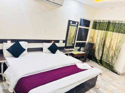 1 dormitorio con cama, mesa y cortinas en Hotel SNR, en Mount Abu