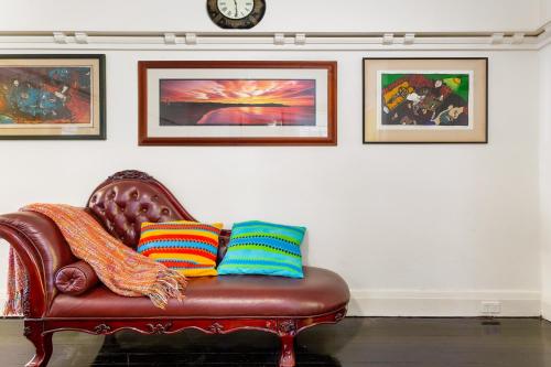 a brown leather couch with three colorful pillows on it at Eclectic Art Deco Apartment in great location in Sydney