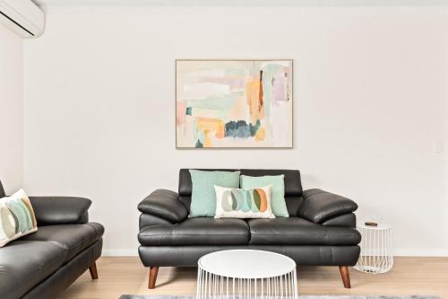 a living room with a black leather couch at Bright and convenient apartment, close to shops in Sydney