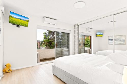 a white bedroom with a large bed and a large window at Bright and convenient apartment, close to shops in Sydney
