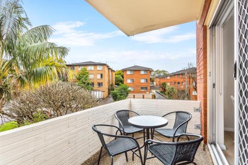 a patio with three chairs and a table on a balcony at Bright and convenient apartment, close to shops in Sydney
