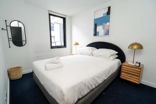 a bedroom with a large white bed and a television at Idyllic 1-Bed Near Popular Shopping Streets in Melbourne