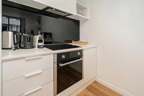 a kitchen with white cabinets and a stove top oven at Idyllic 1-Bed Near Popular Shopping Streets in Melbourne