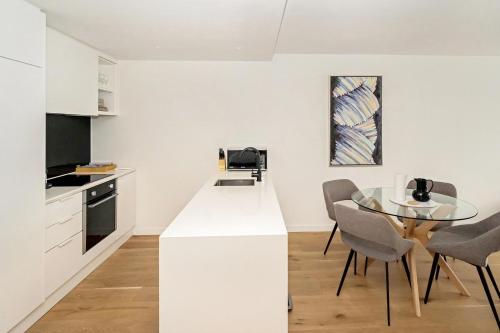 a white kitchen with a glass table and chairs at Idyllic 1-Bed Near Popular Shopping Streets in Melbourne
