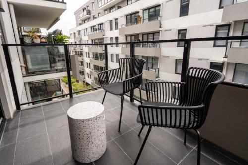 three chairs and a table on a balcony with a building at Idyllic 1-Bed Near Popular Shopping Streets in Melbourne
