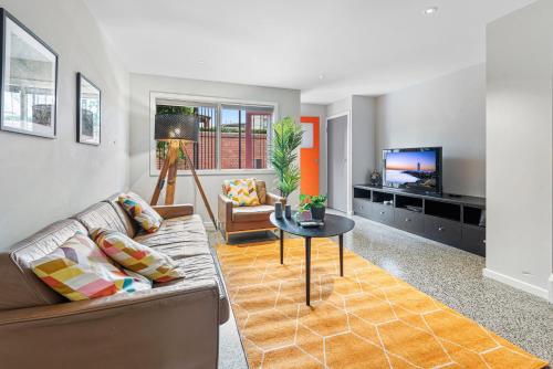 a living room with a couch and a table and a tv at Convenient Bayside Living at the Edge of the City in Melbourne
