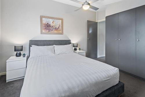 a bedroom with a white bed and a ceiling fan at Convenient Bayside Living at the Edge of the City in Melbourne