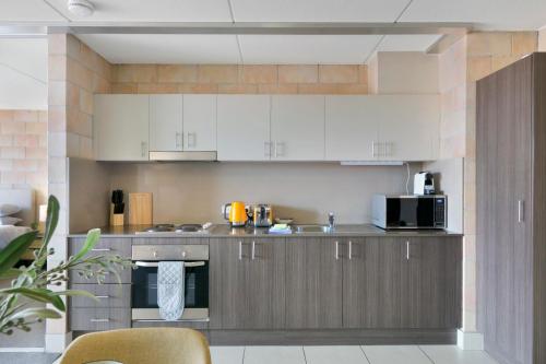 Una cocina con gabinetes blancos y un horno de estufa. en Sleek Apartment with Pool and Rooftop Terrace, en Gold Coast
