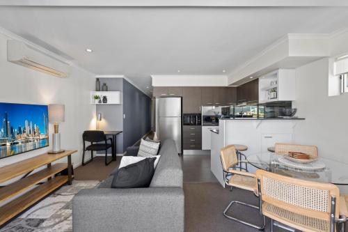 a kitchen and living room with a couch and a table at Chic 2-Bed Apartment & 5 minutes walk to QPAC in Brisbane
