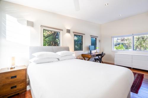 a white bedroom with a white bed and windows at Delightful 4-Bed Home near Centennial Park in Sydney