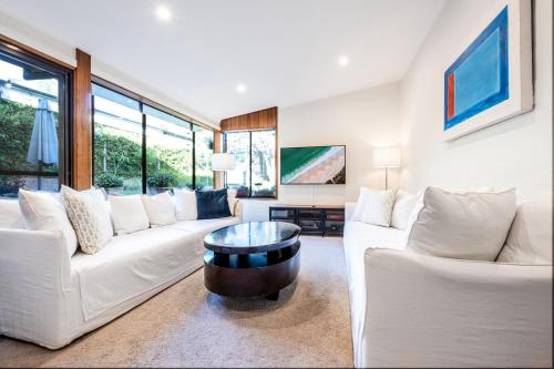 a living room with white couches and a coffee table at Delightful 4-Bed Home near Centennial Park in Sydney