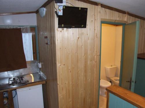 a bathroom with a toilet and a television on the wall at Camping Jonio in Catania