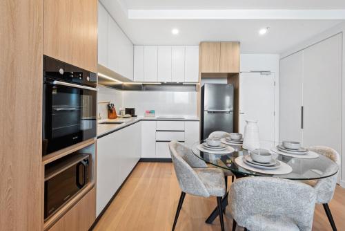 eine Küche mit einem Tisch und Stühlen in einer Küche in der Unterkunft Skyview1-Bed, Infinity Pool, Cinema, Gym & BBQ in Melbourne