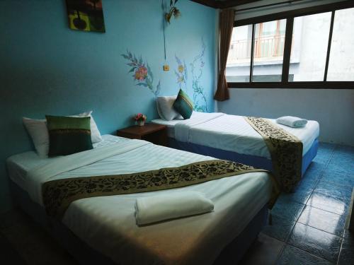 two beds in a room with two windows at StayStable Guest House in Ko Lanta Yai