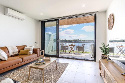 a living room with a couch and a view of the water at Elegant Bay Side 1-Bed Apartment with Views in Batemans Bay