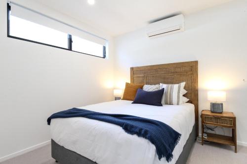 a bedroom with a large bed and two windows at Elegant Bay Side 1-Bed Apartment with Views in Batemans Bay