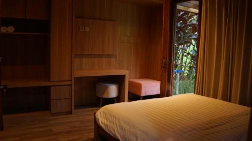 a bedroom with a bed and a desk and a window at Eusabeia Villa And Hot Spring Water in Tomohon