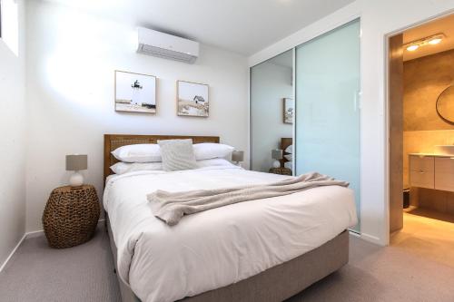 a bedroom with a large bed with white sheets at Elegant 2-Bed Apartment with Stunning Views in Batemans Bay