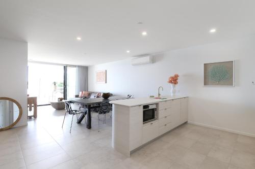 a white kitchen with a table and a dining room at Bayfront Holiday Retreat with Parking in Batemans Bay