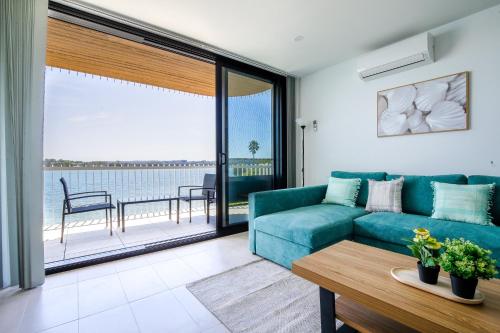 a living room with a blue couch and a view of the ocean at Stunning 1-Bed Bayside Apartment with Superb Views in Batemans Bay