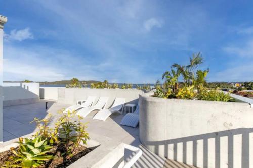 a patio with white chairs and a view of the ocean at Stunning 1-Bed Bayside Apartment with Superb Views in Batemans Bay