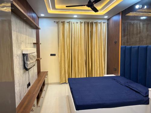 Un dormitorio con una cama azul y un ventilador de techo. en Singhal Residency, en Greater Noida