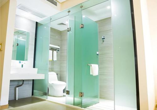 a bathroom with a glass shower with a toilet and a sink at City Comfort Inn Jingzhou Railway Station Fantawild in Caoshi