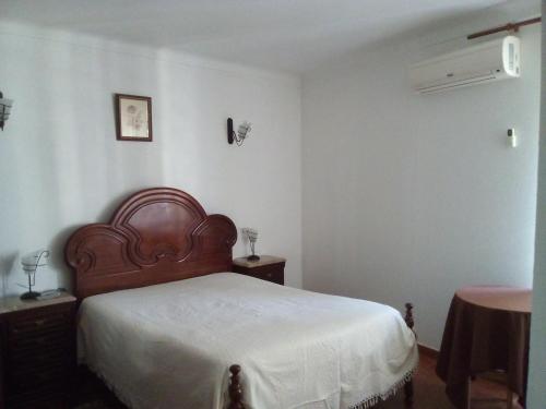 a bedroom with a bed with a wooden headboard at A Casa in Portel