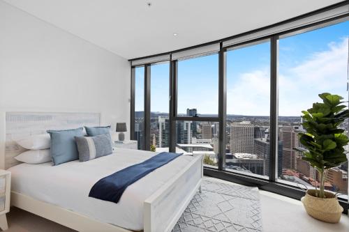 a bedroom with a large white bed and large windows at Breathtaking City Views 1-Bed with Pool, BBQ & Gym in Brisbane