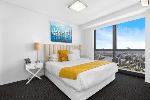 a white bedroom with a large bed and a large window at Stunning River View 2-Bed with Pool, Sauna and Gym in Brisbane