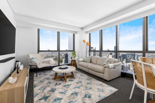 a living room with a couch and chairs and windows at Stunning River View 2-Bed with Pool, Sauna and Gym in Brisbane