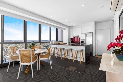 a kitchen with white cabinets and a table and chairs at Stunning River View 2-Bed with Pool, Sauna and Gym in Brisbane
