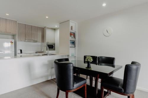 a kitchen with a table and black chairs in a kitchen at Urban 1-Bed Apartment in the Heart of the City in Canberra