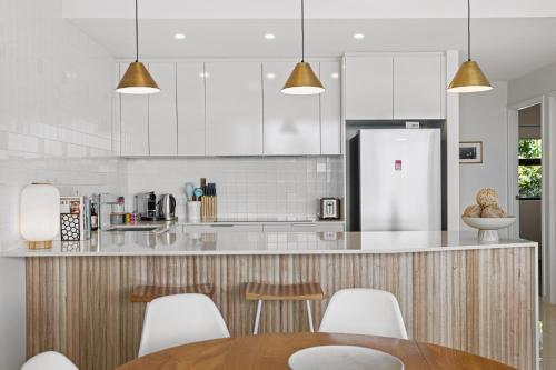 a kitchen with white cabinets and a table and chairs at Gorgeous 3-Bed Apartment with City Views in Brisbane