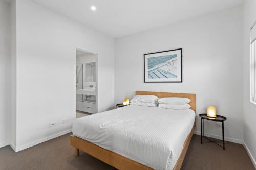a bedroom with a bed with white sheets and two lamps at Gorgeous 3-Bed Apartment with City Views in Brisbane