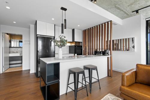 an open kitchen with a bar and stools at Executive 2-Bed Apartment with Views, Gym and Pool in Melbourne