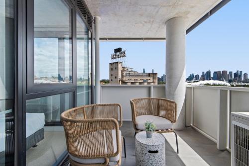 a balcony with two chairs and a view of a city at Executive 2-Bed Apartment with Views, Gym and Pool in Melbourne