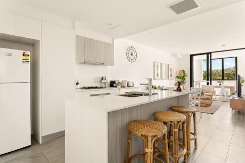une cuisine avec des comptoirs et des tabourets blancs dans l'établissement Coastal 2-Bed Apartment near Beach, à Deewhy
