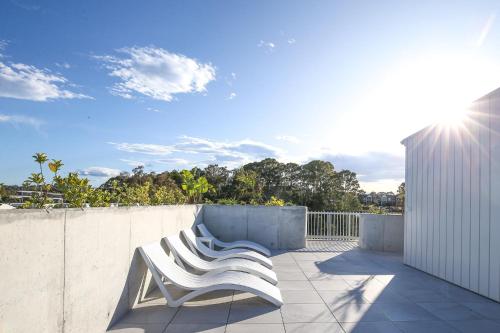 a pair of white chairs sitting on a patio at Oceanside Apartment with Bay Views in Batemans Bay