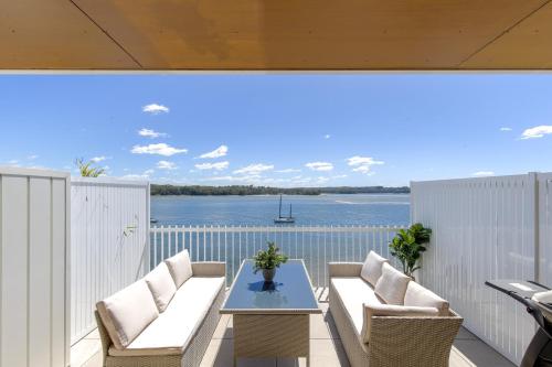 a balcony with a table and chairs and a view of the water at Superb 2-Bed Apartment with Scenic Bay Views in Batemans Bay
