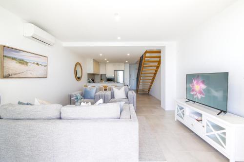 a living room with a couch and a tv at Superb 2-Bed Apartment with Scenic Bay Views in Batemans Bay