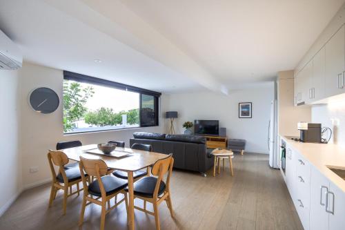 a kitchen and living room with a table and chairs at Chic 2-bed Bridgeview Apartments Batemans Bay in Batemans Bay
