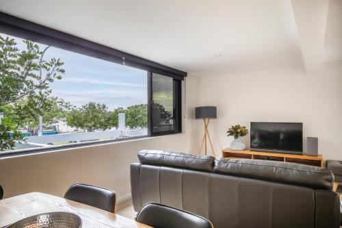 un salon avec un canapé et une grande fenêtre dans l'établissement 2-Bedroom Apartment in the Heart of Batemans Bay, à Batemans Bay