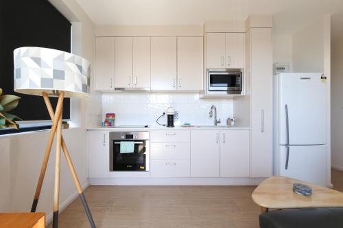 a kitchen with white cabinets and a white refrigerator at Gorgeous 2-bed Bridgeview Apartments Near River in Batemans Bay