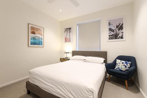 a bedroom with a bed and a blue chair at Gorgeous 2-bed Bridgeview Apartments Near River in Batemans Bay